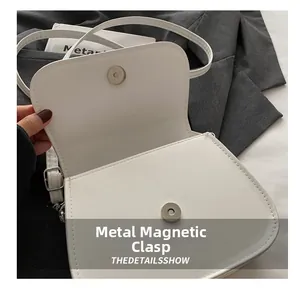 Detail shot of white crossbody bag showing the magnetic closure and leather texture