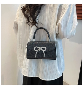 Detail of elegant black sequin evening bag with silver bow clasp and chain strap