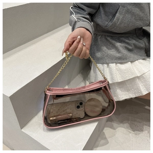 Dettaglio di una borsa trasparente in PVC con bordo rosa e catena dorata su scale