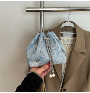 Detail of light blue sequined denim bucket bag with silver chain and pearl pendant