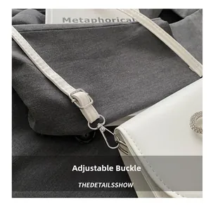 Close-up of adjustable silver metal buckle and hook on white leather shoulder bag strap