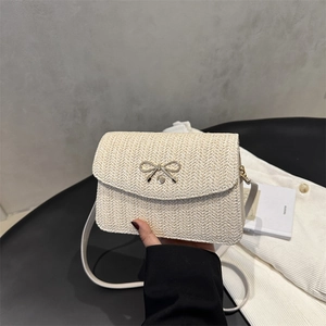 Gros plan sur le sac bandoulière tissé beige avec fermoir décoratif en forme de nœud doré