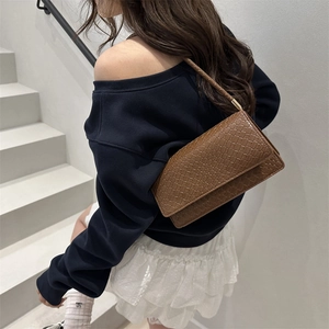 Dark brown faux crocodile leather shoulder bag with gold metal accents on white stairs