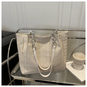 Detail view of woven straw tote bag with chain strap and V-shaped pattern texture