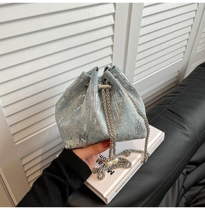 Detail view of light blue sequined denim bucket bag with pearl drawstring chain and silver strap