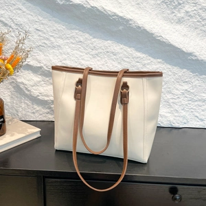 Minimalist beige tote bag with brown leather handles and golden metal rings on stone background