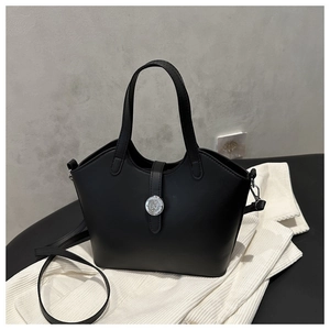 Detail of a black matte leather bucket bag featuring a silver metal embossed knob closure