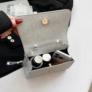 Detail view of silver sequin bag interior holding phone, lipstick and compact powder