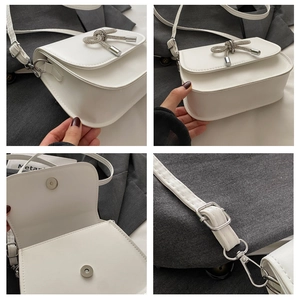 Detail view of white PU leather crossbody bag showing silver rhinestone bow and magnetic snap