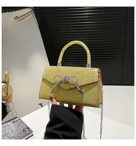 Detailed macro view of the gold glitter clutch bag featuring a sparkling diamond bow accent