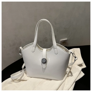 Detail of white glossy leather tote bag showing a silver round buckle and shoulder strap