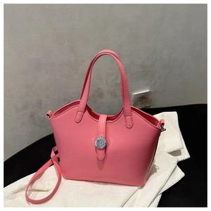 Close-up of pink glossy leather handbag with silver clasp on white knit sweater