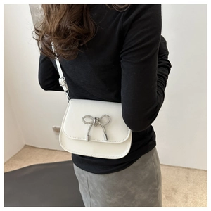 Back view of a white leather crossbody bag featuring a sparkling rhinestone butterfly detail