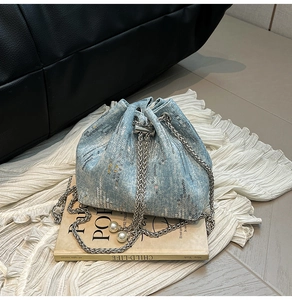 Detail of light blue denim bucket bag with silver sequins and pearl chain accents