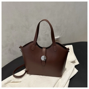 Detail view of the dark brown leather bucket bag showing fine texture and silver logo