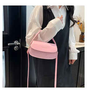 Detail of pink semi-circle handbag featuring textured leather and gold logo lettering