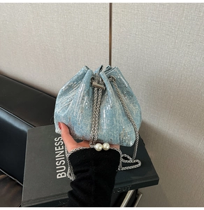 Detail of blue sequin denim bucket bag with silver chain and pearl accents