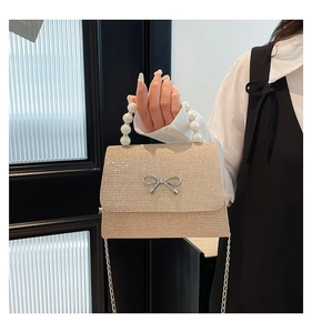 Detailed shot of champagne gold sequin handbag with pearl handle and silver bow decoration