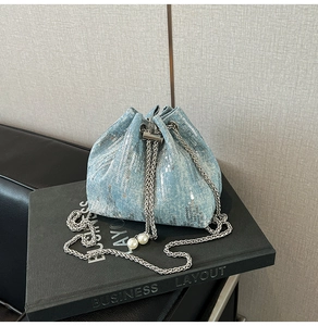 Detail of blue denim bucket bag with silver sequins, pearls and metal chain