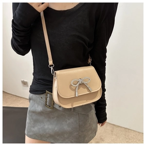 Close-up of apricot leather crossbody bag featuring a sparkling rhinestone butterfly buckle