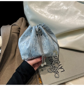 Detail of denim bucket bag with silver sequins and pearl tassel chain drawstring