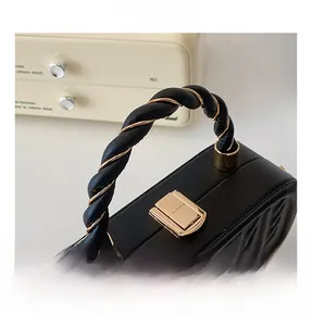 Detail of black embossed handbag featuring golden metal clasp and woven handle texture