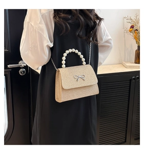 Detail of glittery mini square bag with large pearl handle and metal bow decoration