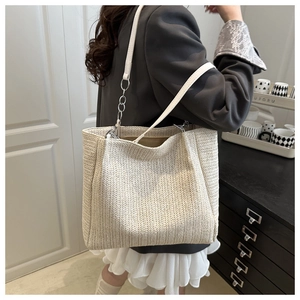 Detailed view of large straw tote bag featuring herringbone weave and leather chain strap