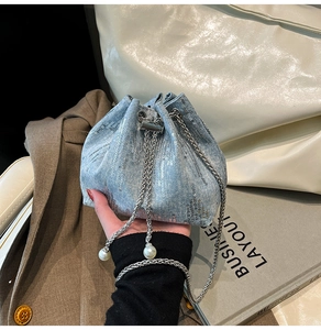 Detail of blue denim bucket bag with sparkling sequins and elegant pearl charm strap