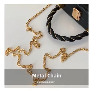Detail of premium gold hardware chain and buckle on minimalist black leather handbag