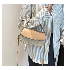 Close-up of a semi-circular crossbody bag with beige leather flap and grey textured body