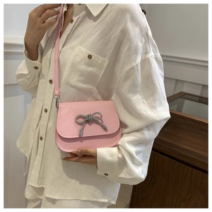 Pink crossbody bag with rhinestone butterfly charm shown on model in white shirt
