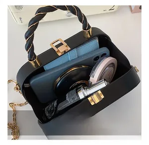 Internal capacity of black chain box bag showing phone, wallet and cosmetics inside
