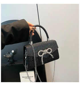 Detail of black sequin evening bag with sparkling rhinestones and silver bow buckle