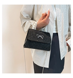 Fashionable black sequin mini bag with pearl handle and metal bow shown on a model