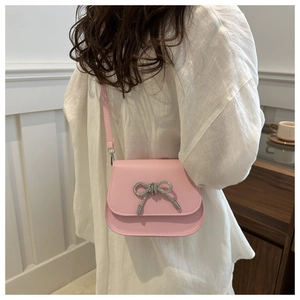 Detail shot of a pink crossbody bag with a sparkling silver butterfly bow on the flap