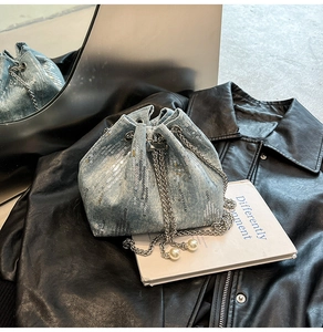 Detail of light blue denim bucket bag with silver sequins and pearl chain accent
