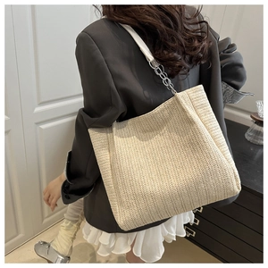 Detail of large woven tote bag featuring creamy V-shaped texture and chain strap