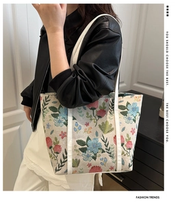 Detail of floral embroidery and white leather straps on a large canvas tote bag