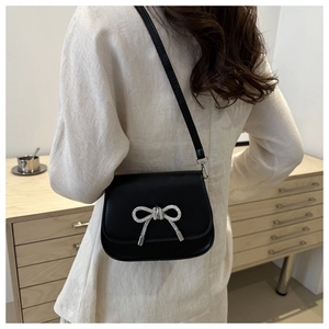 Detail of black crossbody bag featuring a silver rhinestone butterfly on PU leather