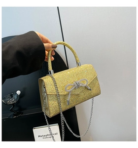 Detail of glitter evening handbag with rhinestone bow and silver chain strap