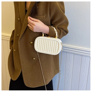 Detail of white embossed chain bag featuring knit texture and gold metal buckle