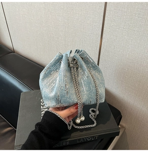 Detail of light blue denim bucket bag with silver sequins and pearl chain drawstring