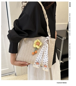 Detail of woven straw tote bag with sunflower pendant and patterned scarf handle decor