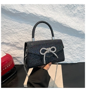 Close-up of black sequin evening clutch featuring a sparkling rhinestone bow detail