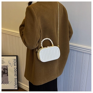 Detail of white box bag with 3D embossed knit texture and dual-tone spiral handle