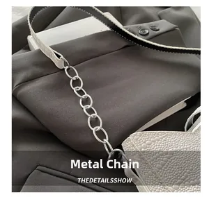 Detail of silver chain metal connection on white ostrich texture shoulder bag strap