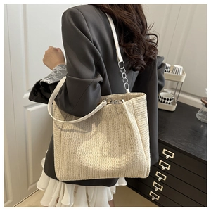 Detail of beige straw tote bag with V-shaped herringbone weave and metal chain strap