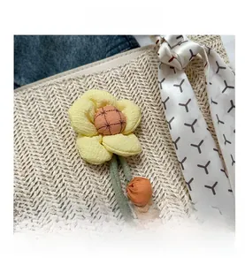 Detail shot of a yellow fabric flower pendant hanging on a woven straw tote bag