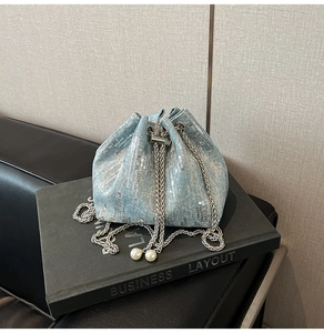 Detail of light blue denim bucket bag with silver sequins, chain drawstring, and pearls